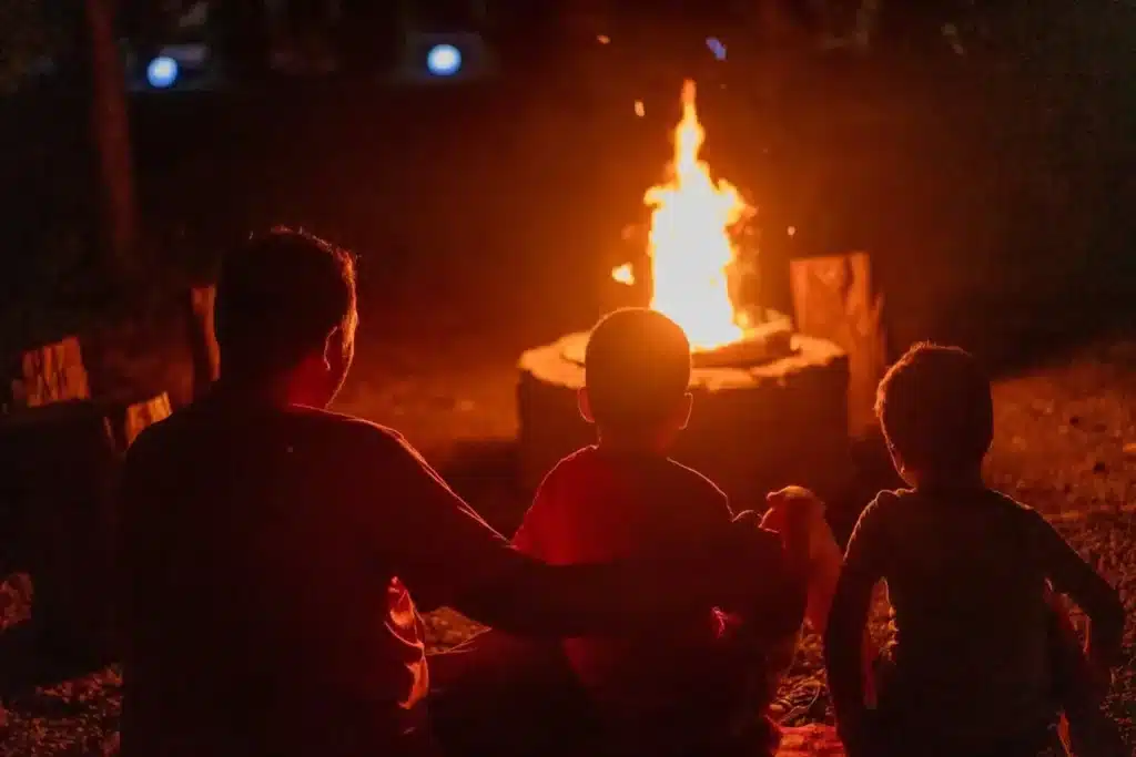 Famille autour d'un brasero extérieur flamboyant avec une ambiance cosy