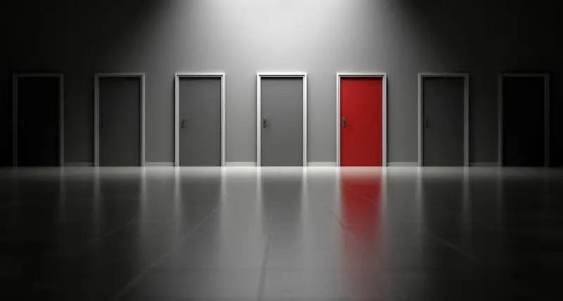 Plusieurs portes toutes grise sauf une seul rouge dans une grande piĂšce.
